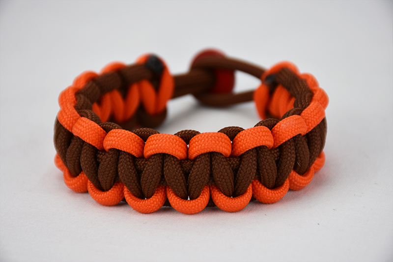 brown orange and brown paracord bracelet unity band with red button in back, picture of a brown orange and brown paracord bracelet unity band with red button fastener in the back on a white background
