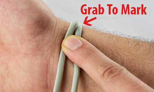 how to size a paracord bracelet, picture of a wrist with rope around it and an arrow pointing to where the rope meets itself and says grab to mark