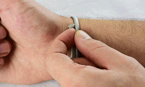 how to size a paracord bracelet, gif of a man grabbing rope to mark where his wrist size is and than measuring the rope on a ruler to determine what size paracord bracelet to get