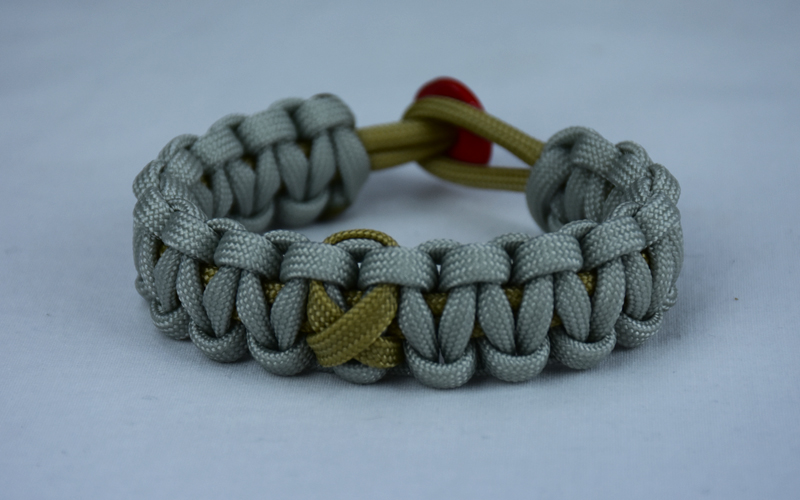 gold and grey pediatric support paracord bracelet with red button back and gold ribbon 